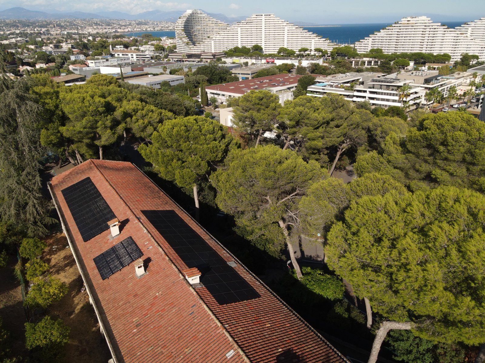 Centrale photovoltaïque sur la toiture de l'école des Maurettes à Villeneuve-Loubet, vue de drone face à la baie des Anges