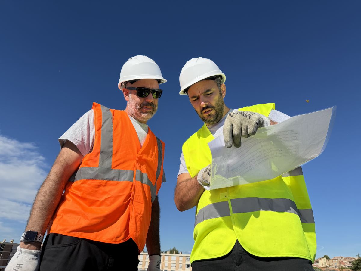 Deux techniciens casqués contrôlent un module photovoltaïque avant la pose