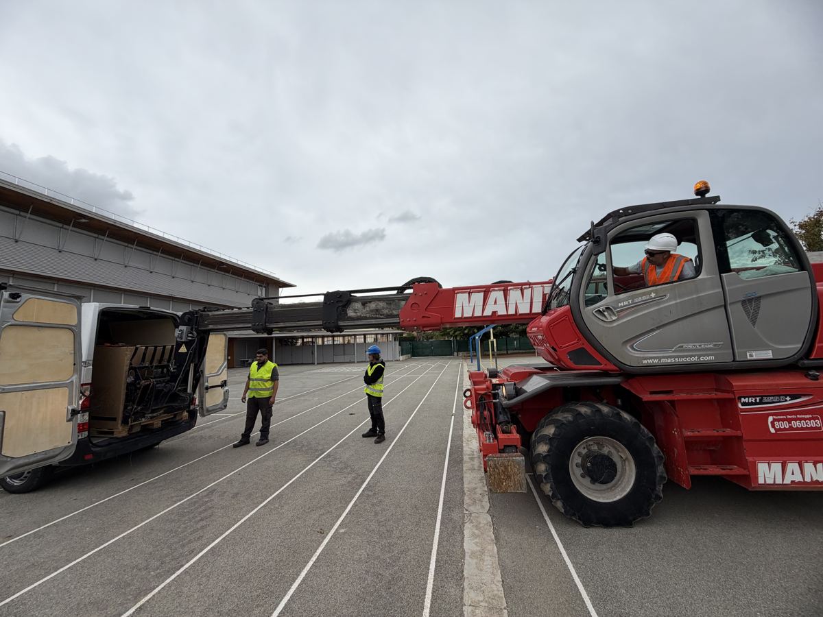 Trois techniciens pendant le levage des modules photovoltaïques au chariot télescopique